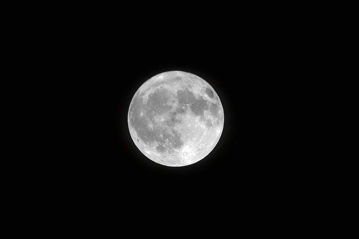 Landscape shot of a white full moon with black color in the background