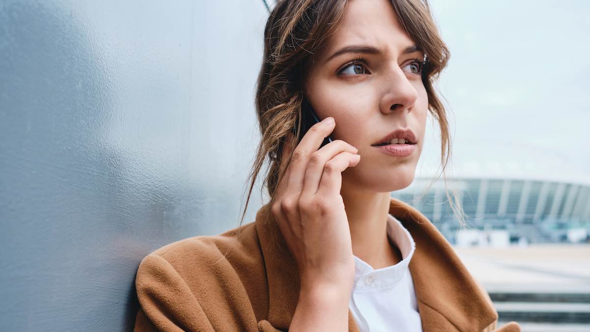 Portrait of pensive businesswoman in coat talking on cellphone outdoor